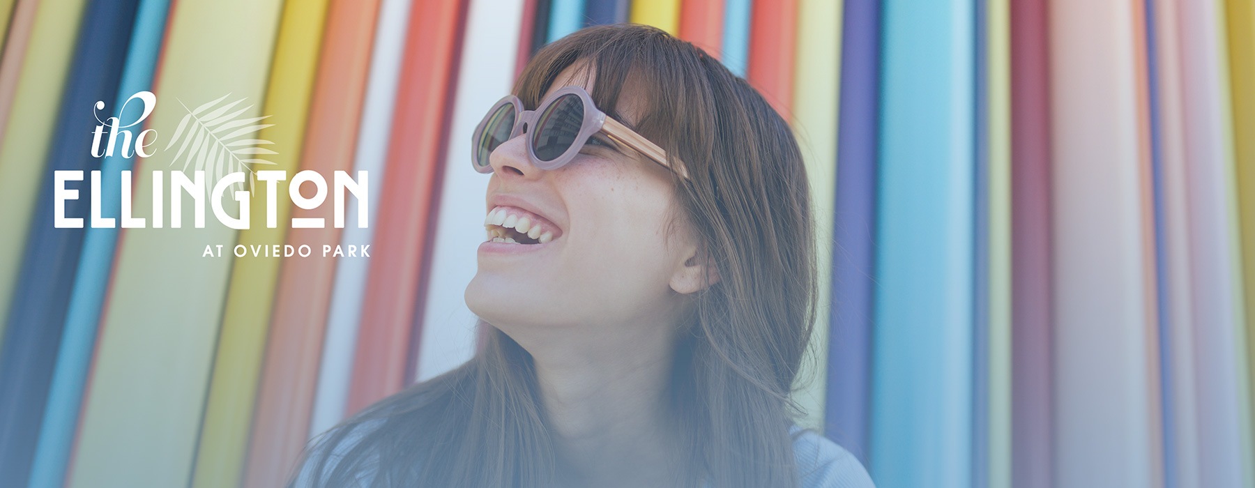 lifestyle image of a young woman smiling in front of a colorful background